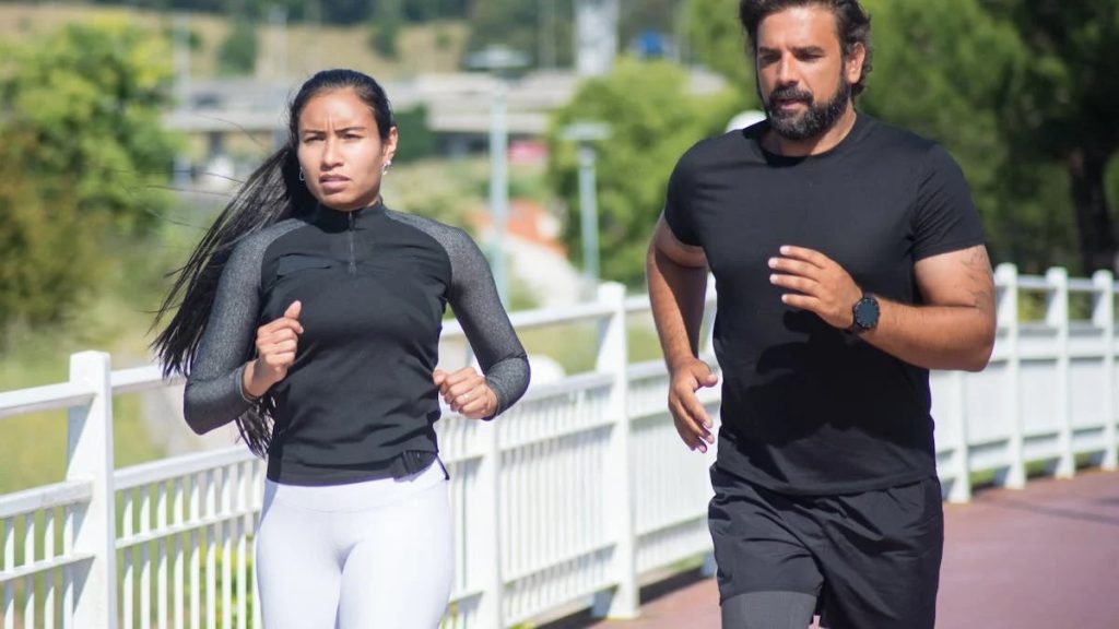 Active couple jogging outdoors on a sunny day, promoting fitness and healthy lifestyle.